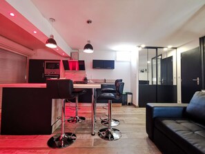 Eine moderne Küche mit Essbereich, Barhocker und einer Couch.