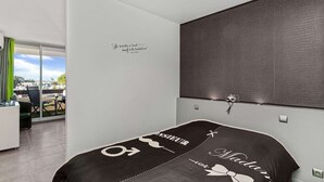 A modern hotel room with a bed, a desk, and a view of the outside. - CARESSE - Studio Port Nature PN620 - Luxe - 2 people (AGDE)