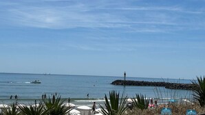 A beach with a lighthouse, calm sea, and people enjoying the water. - CARESSE - Studio Port Nature PN620 - Luxe - 2 people (AGDE)
