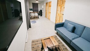 Egy modern nappali, amelyben van egy kanapé, egy dohányzóasztal, valamint egy étkezősarok székekkel és asztallal.