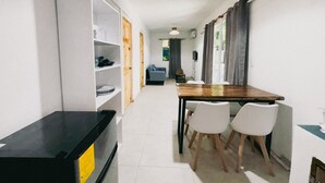 Un espace de vie compact comprenant un coin cuisine, un coin repas et un petit coin salon.
