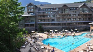 Ett hotell med en stor pool, utomhusmöbler och en vacker bergsutsikt.