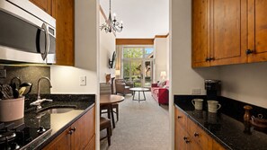 Una cocina con armarios de madera, microondas, fregadero y comedor con mesa y sillas.