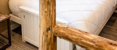 Een slaapkamer met een groot bed, houten hoofdeinde, twee ramen en een wandlamp.