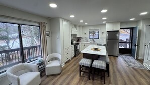 A modern kitchen with white cabinets, a central island, and a view of the outdoors. - Epic Renovated Slopeside Unit feet from Camelback Mountain- Laurel Glade Trail. (Tannersville)