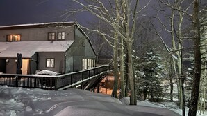 A snow-covered landscape with a large house featuring a balcony and a staircase leading to the entrance. - Epic Renovated Slopeside Unit feet from Camelback Mountain- Laurel Glade Trail. (Tannersville)