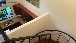 Un escalier avec une rampe en métal menant à une cuisine dotée d’une fenêtre et d’un ventilateur de plafond.