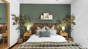 A bedroom with a bed, two bedside tables, a nightstand, a mirror, and two potted plants. - Stillwater by Avantstay Hot Tub + Theater + Game Room Firepit + BBQ Near Lakes, Skiing & Hiking (Pocono Summit)