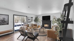 Ein modernes Wohnzimmer mit Kamin, Sofa, Couchtisch und Fernseher.