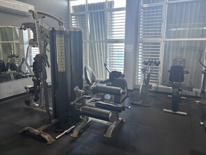 A gym with exercise equipment, large windows, and a mirror.