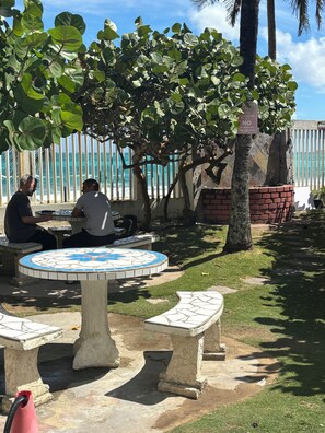A patio area with a tiled table and benches, a brick wall, and a view of the ocean.