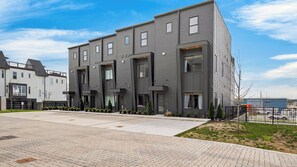 A modern multi-story residential building with a flat roof, large windows, and a paved entrance area. - That 70s Show by Avantstay Skyline Views + Rooftop Hot Tub + Bumper Pool Mins to Broadway + Nissan Stadium + Germantown (Nashville)