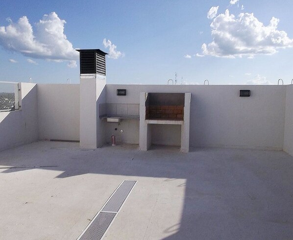 A rooftop terrace with a small enclosed area, possibly for a grill or barbecue, and a ventilation unit.