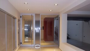 Un couloir moderne avec des portes en verre, un plancher poli et un éclairage encastré.