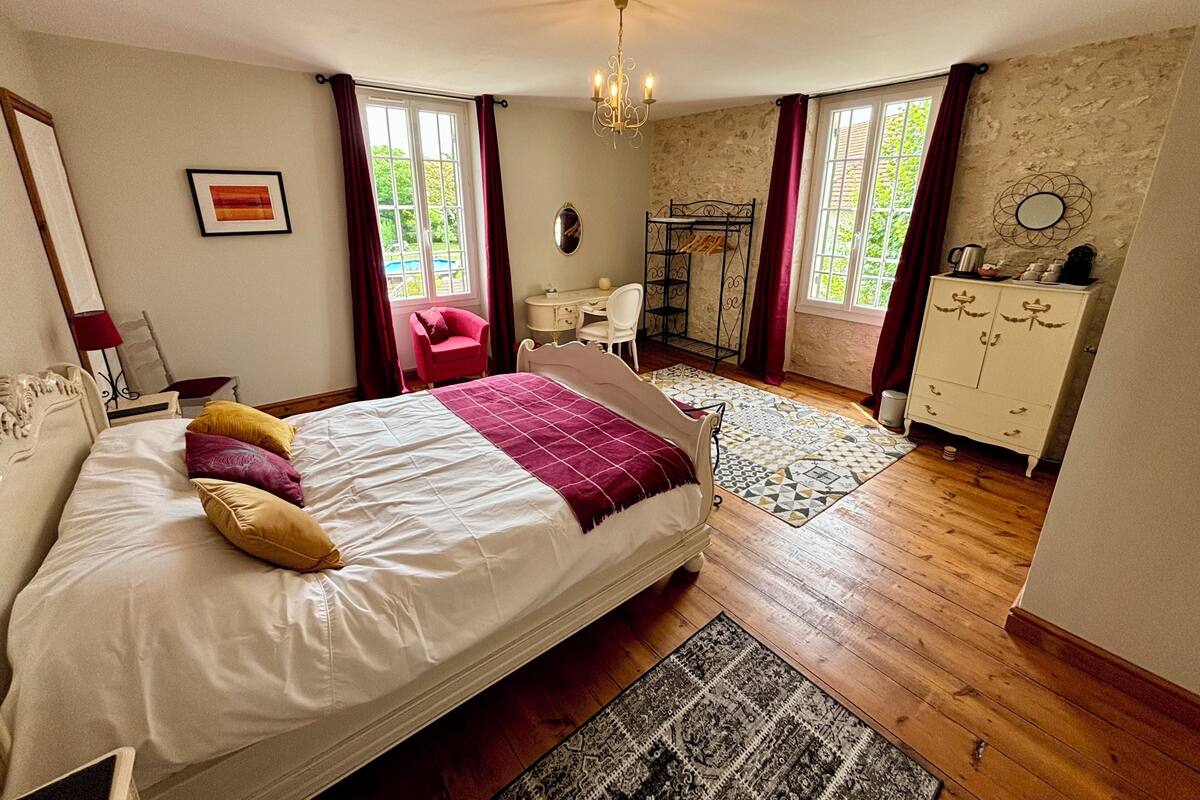 A bedroom with a bed, a desk, a chair, a wardrobe, and a window with curtains.
