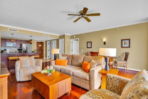 A living room with a sofa, armchairs, a coffee table, and a dining area with a table and chairs. There is a kitchen in the background. - Honua Kai | Ocean View 7 BR, Sleeps 20 | Car Incl. w/ 6+ Nights | HKK ML-3356 by KBM (Lahaina)