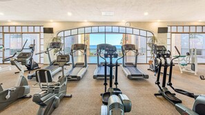 Un gimnasio con cintas de correr, elípticas y máquinas de pesas, con vistas panorámicas.