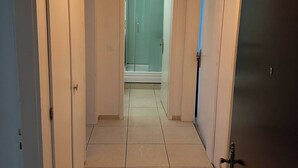 A hallway with a glass door leading to a bathroom, a ceiling light, and tiled flooring. - Furnished Apartment in Baden (Baden)