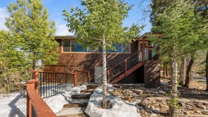 A wooden staircase leading to a modern house with a metal railing, surrounded by trees and snow. - Honey Bear Cabin (Big Bear Lake)