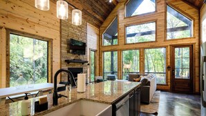 A spacious kitchen with granite countertops, a large island, and a built-in oven. - Modern Glass Cabin w/ Hot Tub & Outdoor Lounge (Broken Bow)
