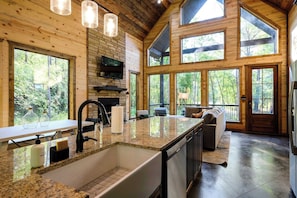 A spacious kitchen with granite countertops, a large island, and a built-in oven. - Modern Glass Cabin w/ Hot Tub & Outdoor Lounge (Broken Bow)