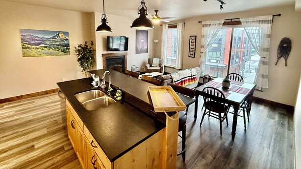 A modern kitchen with a central island, wooden cabinets, and pendant lighting.