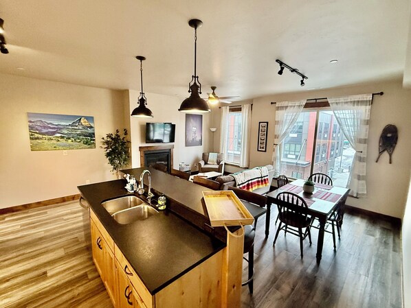 A modern kitchen with a central island, wooden cabinets, and pendant lighting.
