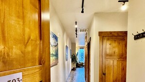A hallway with wooden doors, a sign reading '303', and a view into a room with a plant.