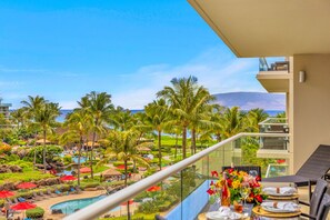 Ein Balkon mit Blick auf ein Resort-Pool, Palmen und einen Berg im Hintergrund.