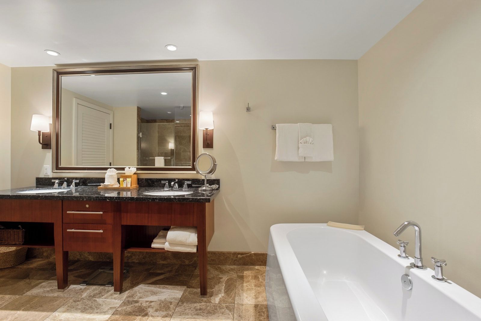 Une salle de bain avec un meuble-lavabo à deux vasques, un grand miroir, une baignoire et un porte-serviettes.