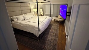 Un dormitorio con cama con dosel, ventilador de techo, televisor y mesita de noche.