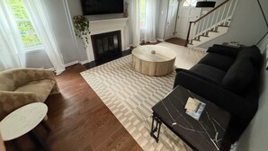 Una sala de estar con chimenea, un sofá, una mesa de centro y una televisión.
