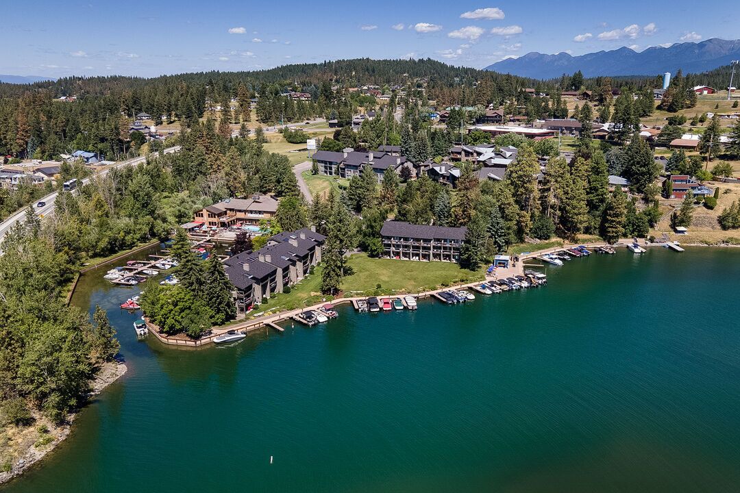 An aerial view of a lakeside community with residential buildings, a marina, and a golf course.
