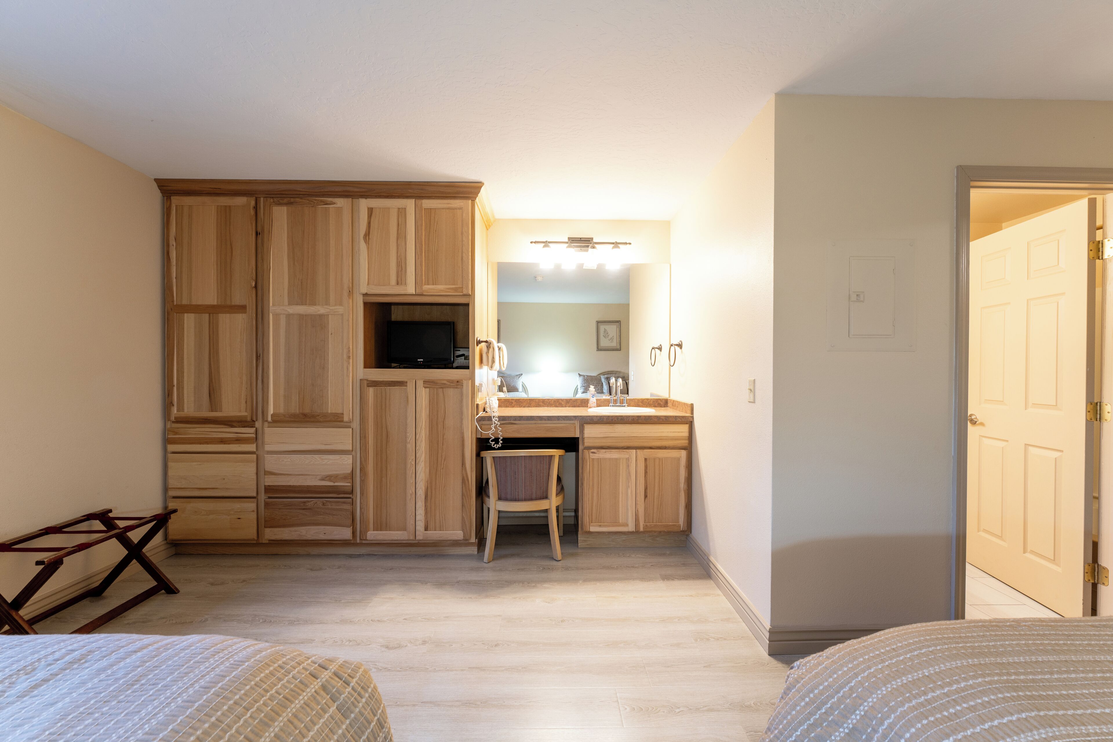 A bedroom with a bed, a desk with a chair, a wardrobe, and a bathroom visible through an open door.