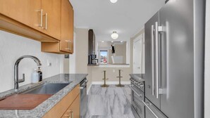 Una cocina moderna con armarios de madera, un refrigerador de acero inoxidable y una encimera de mármol.