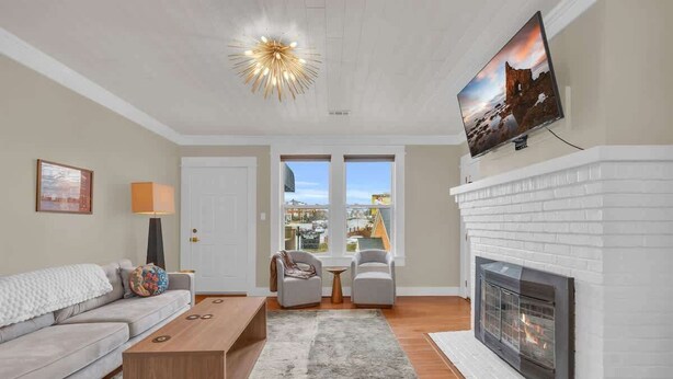 Una sala de estar moderna con chimenea, sofá, mesa de centro y televisor montado en la pared.