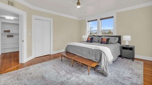 Un dormitorio con cama, mesitas de noche, un banco, armario y ventana.