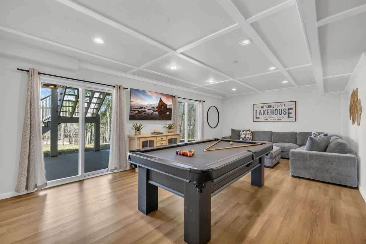 Une table de billard dans une pièce où se trouvent un canapé et un panneau indiquant : « Bienvenue dans notre maison au bord du lac. »