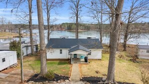 A single-story house with a front porch, a small deck, and a view of a lake.