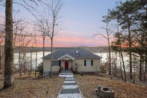 A house with a red door, a front porch, and a gravel path leading to the entrance. - Private Dock & Game Rm: Lake Home w/ Fire Pit (Waterloo)