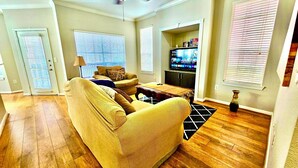 A living room with a sofa, a coffee table, a ceiling fan, and a television. - Convenience-Downtown-MedCtr-Entertainment-Westheimer-NRG (Houston)