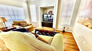 A living room with a sofa, a coffee table, and a TV in the background. - Convenience-Downtown-MedCtr-Entertainment-Westheimer-NRG (Houston)