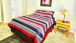 A bedroom with a bed, a nightstand, a lamp, a door, and a framed picture on the wall. - Convenience-Downtown-MedCtr-Entertainment-Westheimer-NRG (Houston)