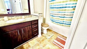 A bathroom with a sink, mirror, toilet, and shower curtain. - Convenience-Downtown-MedCtr-Entertainment-Westheimer-NRG (Houston)