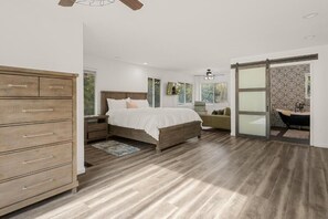 Un dormitorio con cama, cómoda de madera y baño con bañera.