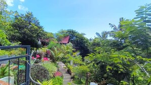 A lush garden with a pathway leading to a building with a red roof.