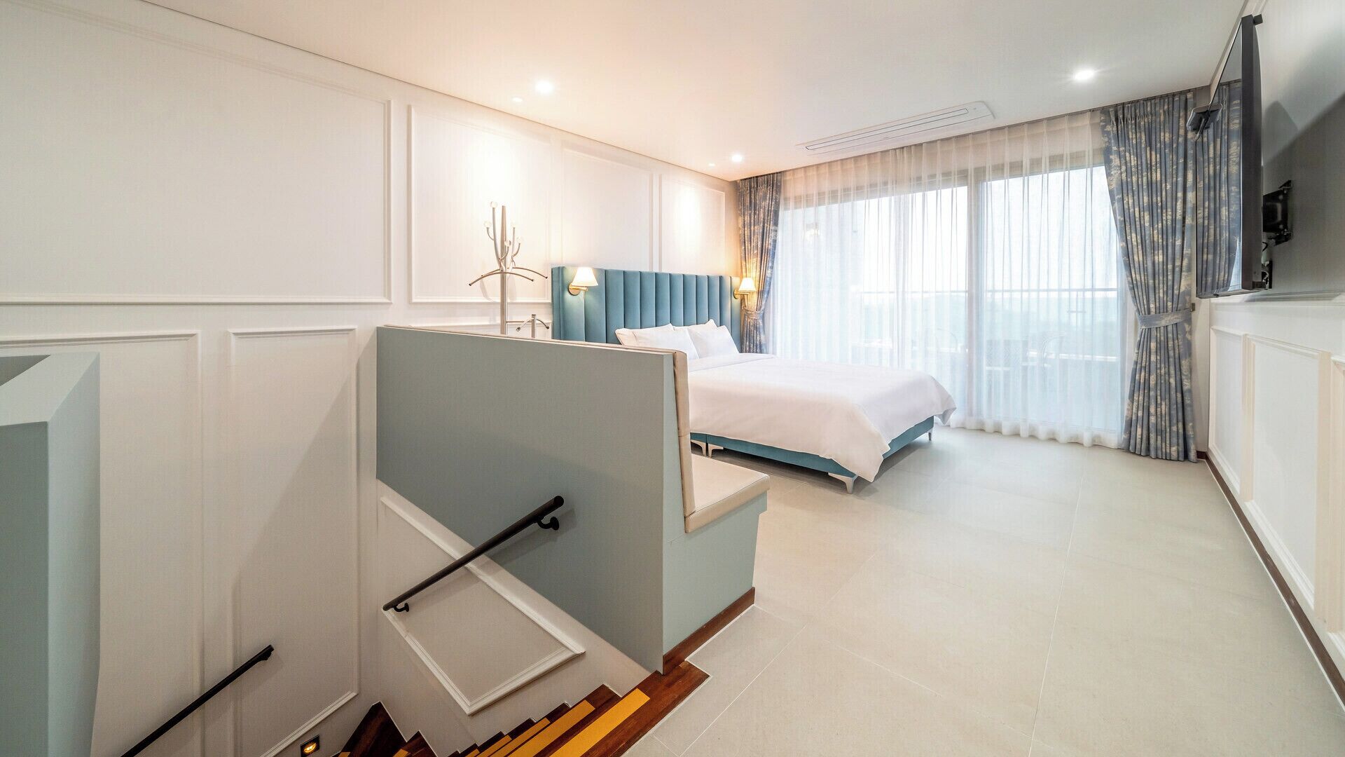 A hotel room with a bed, a desk, and a view of the outdoors.