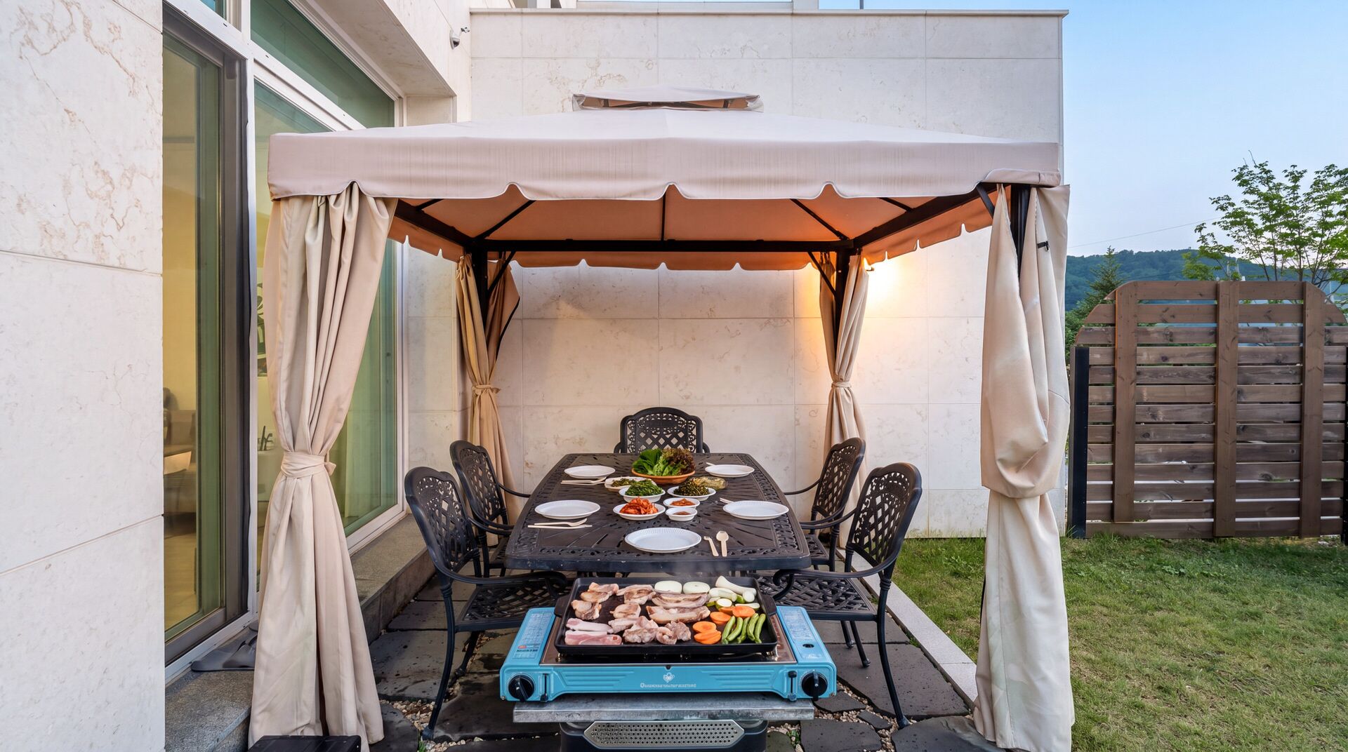 An outdoor patio with a covered table, chairs, and a grill.