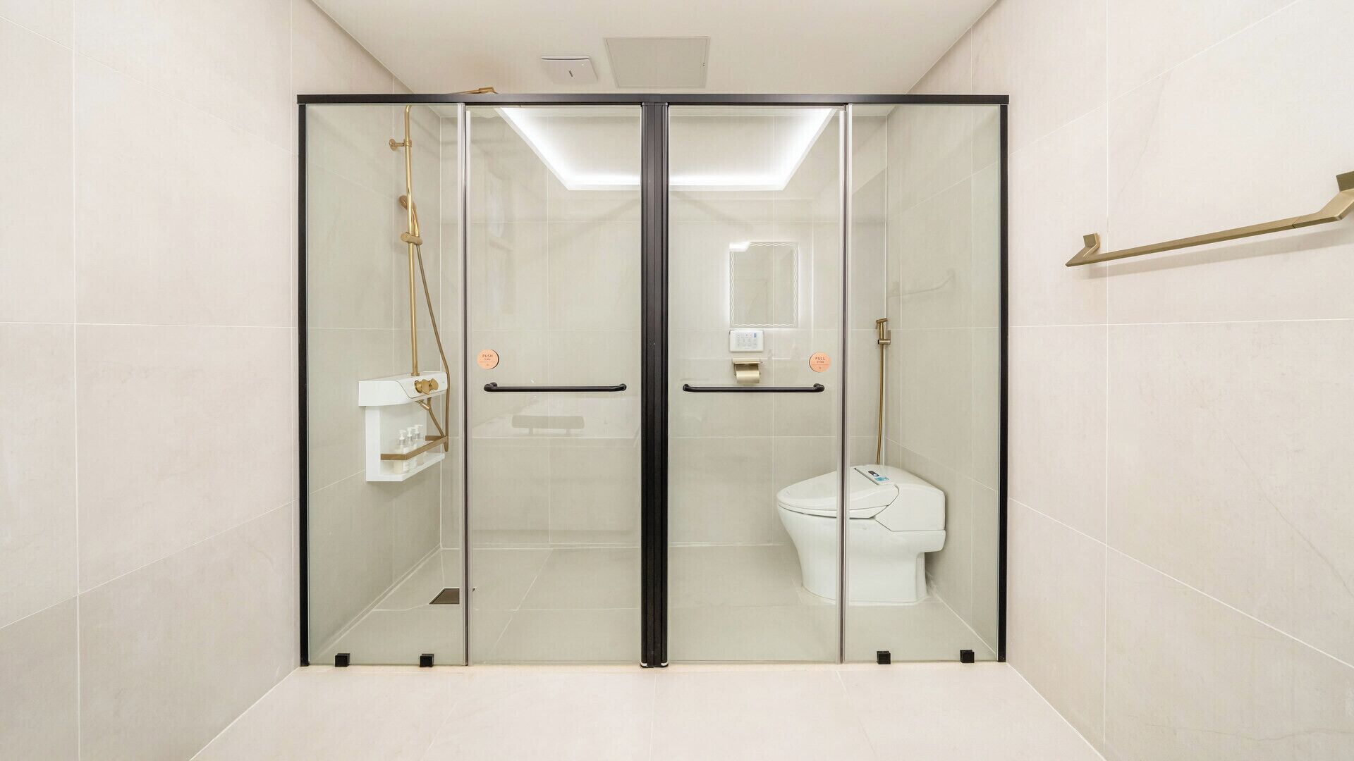 A glass-enclosed shower stall with a toilet and a towel rack.