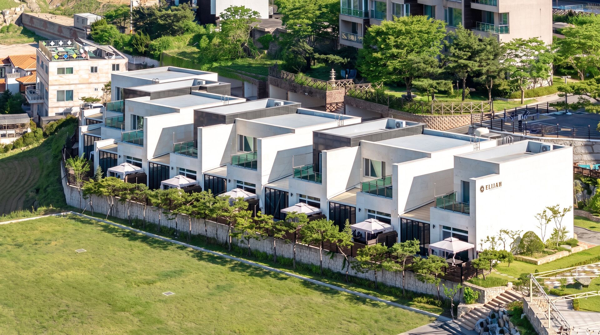 Un hôtel moderne doté d’un toit plat, de nombreux balcons et d’un jardin aménagé.